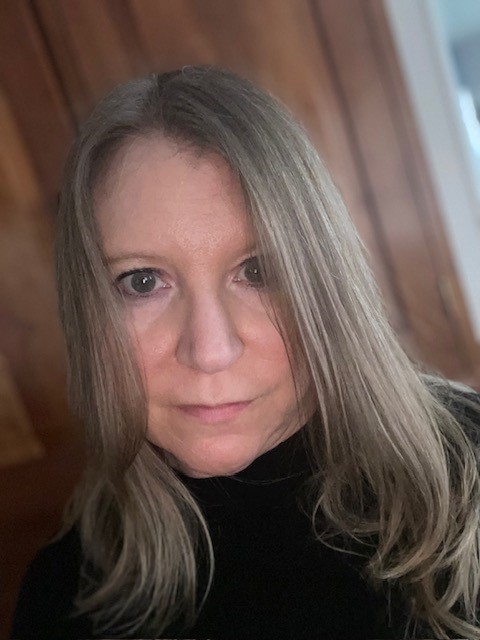 headshot of woman with long light brown hair wearing a black shirt
